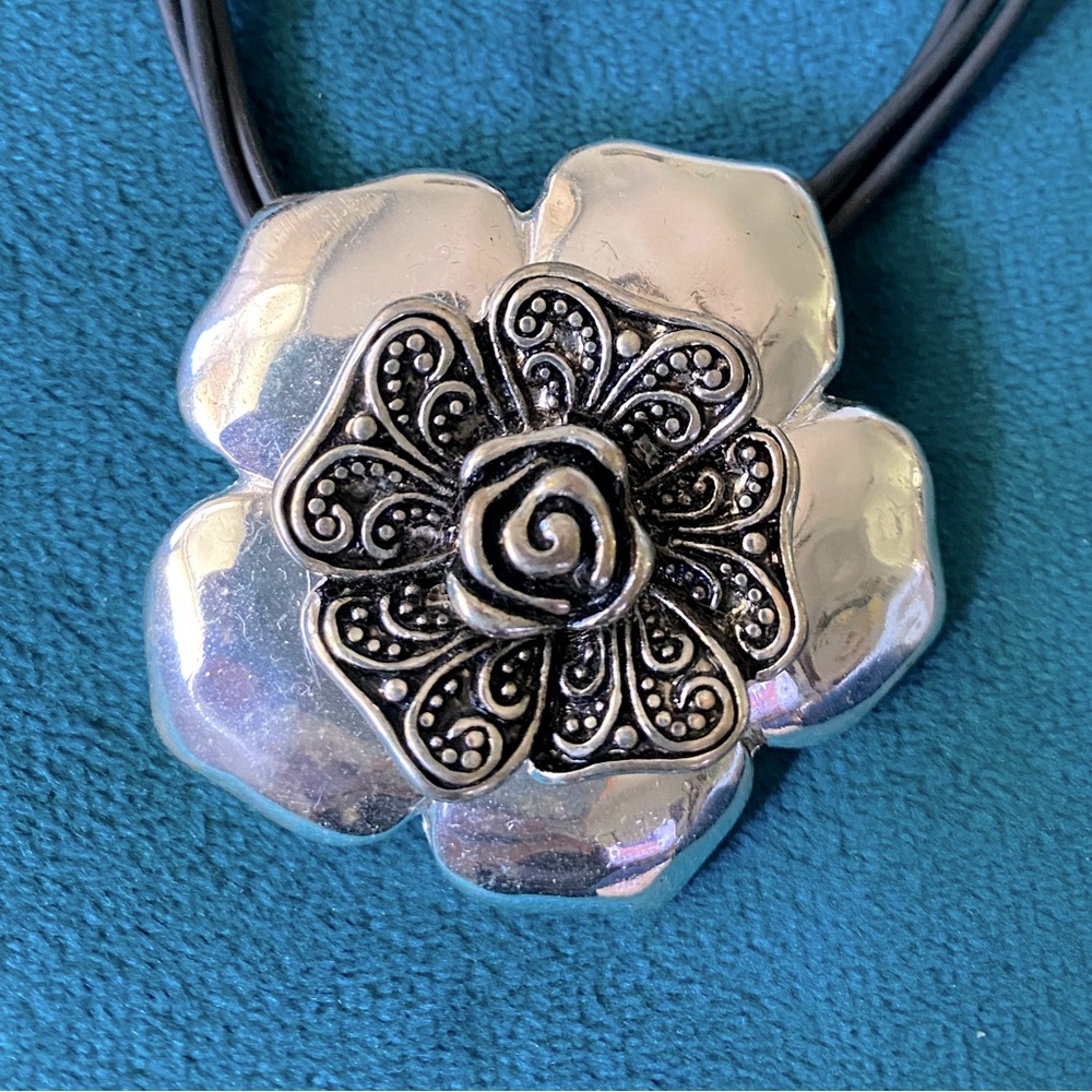 Silver rose pendant on black leather cord.